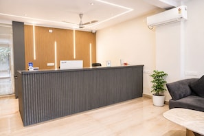 A reception desk with a nameplate, a ceiling fan, and a potted plant. - Axon Bellandur Phase 2 (Bengaluru)
