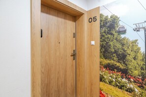Una porta de fusta amb el número 05, un interruptor de llum i una telecabina al fons.