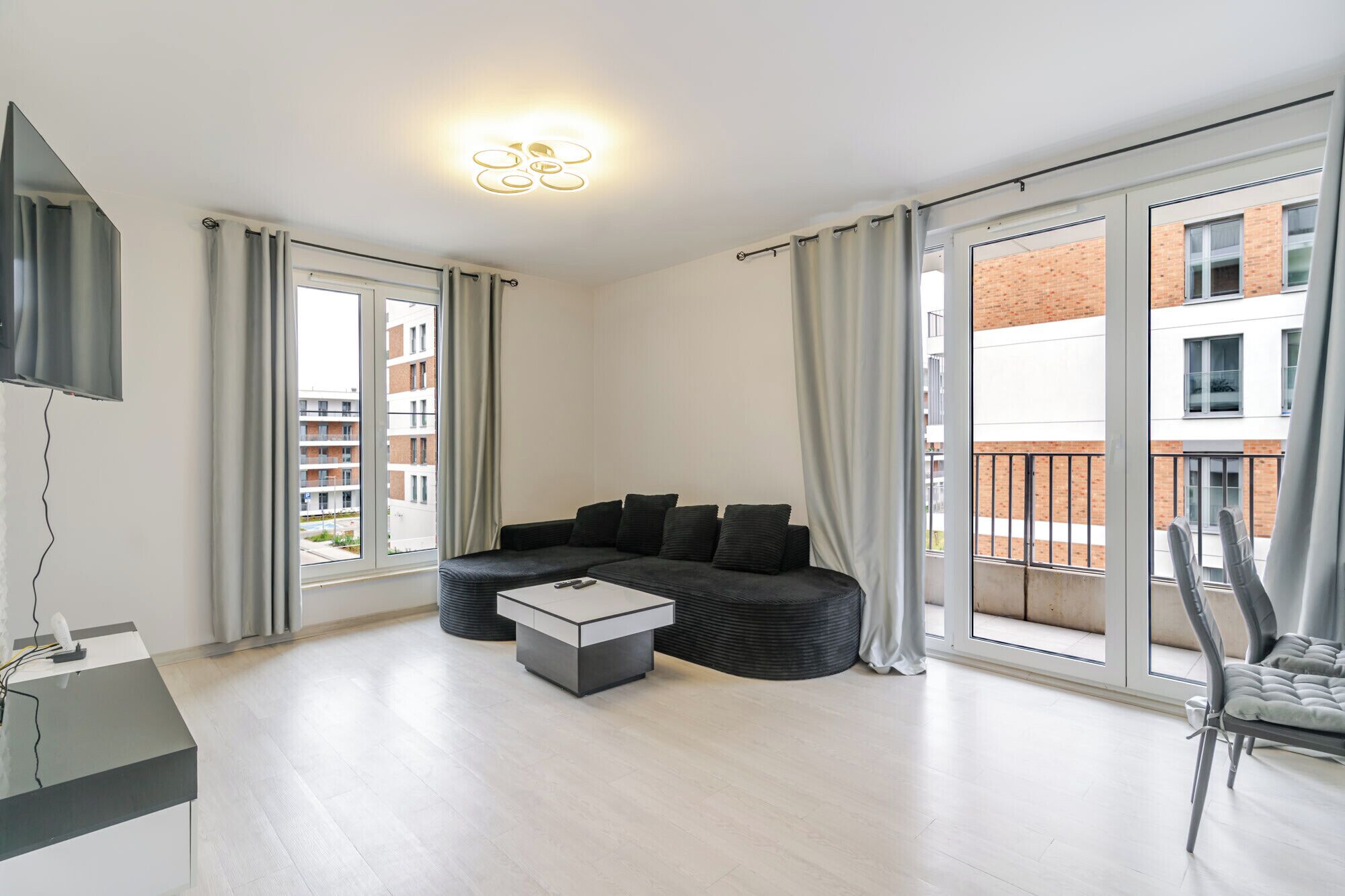 Una sala de estar moderna con un sofá, una mesa de centro y un televisor en la pared.