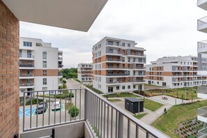 Un complex d'apartaments modern amb diversos edificis, balcons i una zona d'aparcament amb punts de càrrega per vehicles elèctrics.