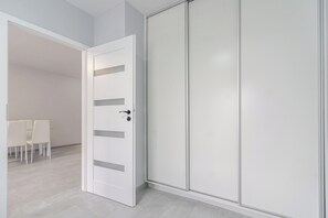 A room with a white wardrobe, a door, and a seating area with chairs. - Harmony Park Modern Apartment (Chorzów)