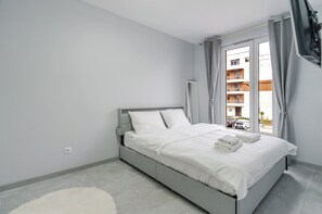 A modern bedroom with a bed, a large window, and a view of a building outside. - Harmony Park Modern Apartment (Chorzów)