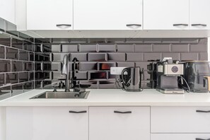 Eine moderne Küche mit einer Edelstahl-Spüle, einer Kaffeemaschine und einem eingebauten Backofen.