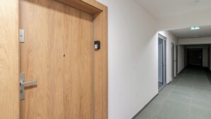 A hallway with a wooden door, a metal handle, and a small electronic lock. - Harmony Park Modern Apartment (Chorzów)