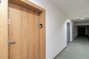 A hallway with a wooden door, a metal handle, and a small electronic lock. - Harmony Park Modern Apartment (Chorzów)