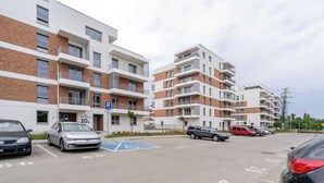 A multi-story residential building with a parking area in front. - Harmony Park Modern Apartment (Chorzów)