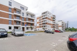 A multi-story residential building with a parking area in front. - Harmony Park Modern Apartment (Chorzów)