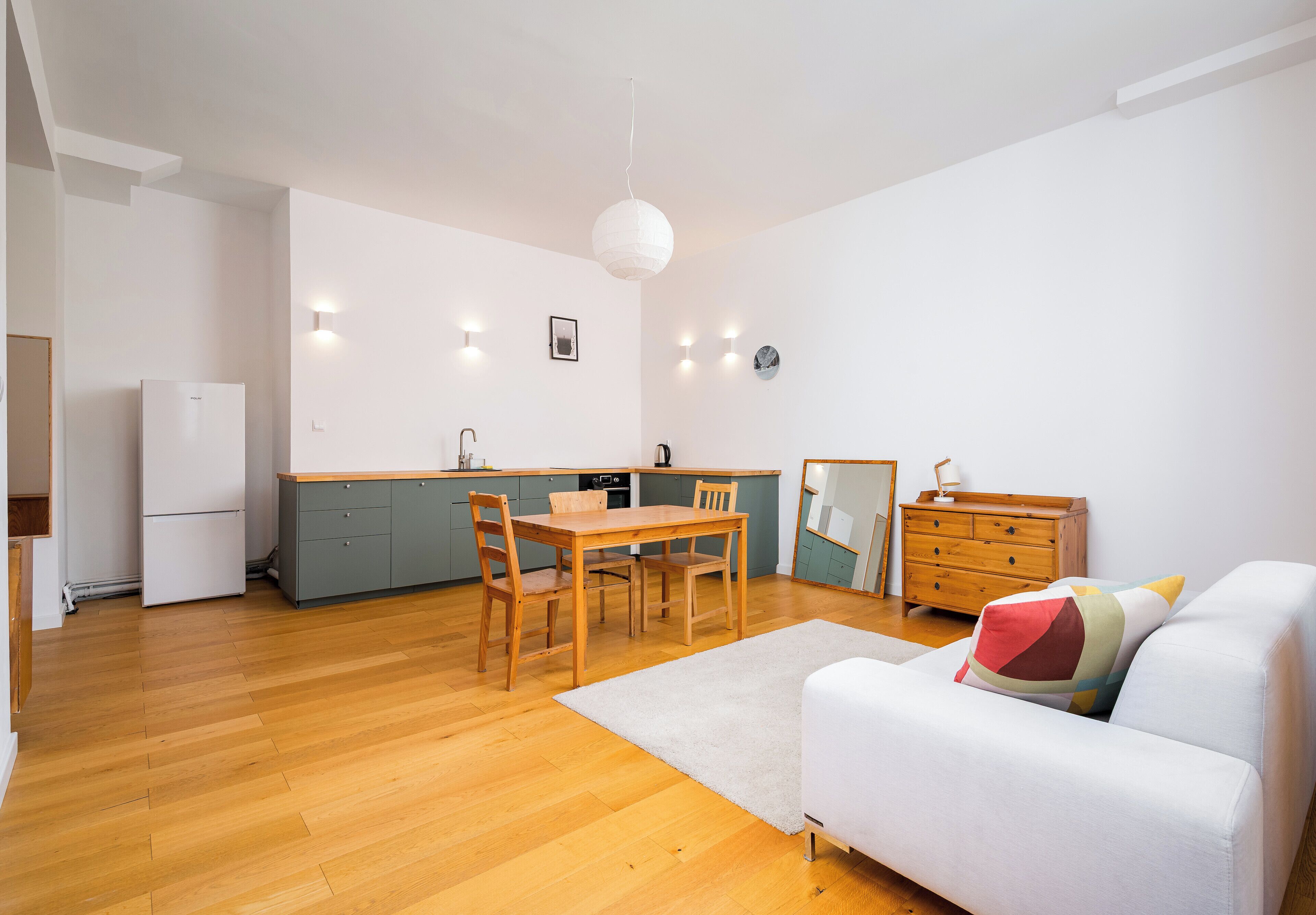 Una cocina moderna con una mesa de comedor, sillas, un sofá y un espejo grande.