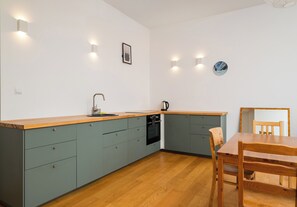 Eine moderne Küche mit Holzarbeitsplatte, integrierten Geräten und einem Essbereich mit Tisch und Stühlen.