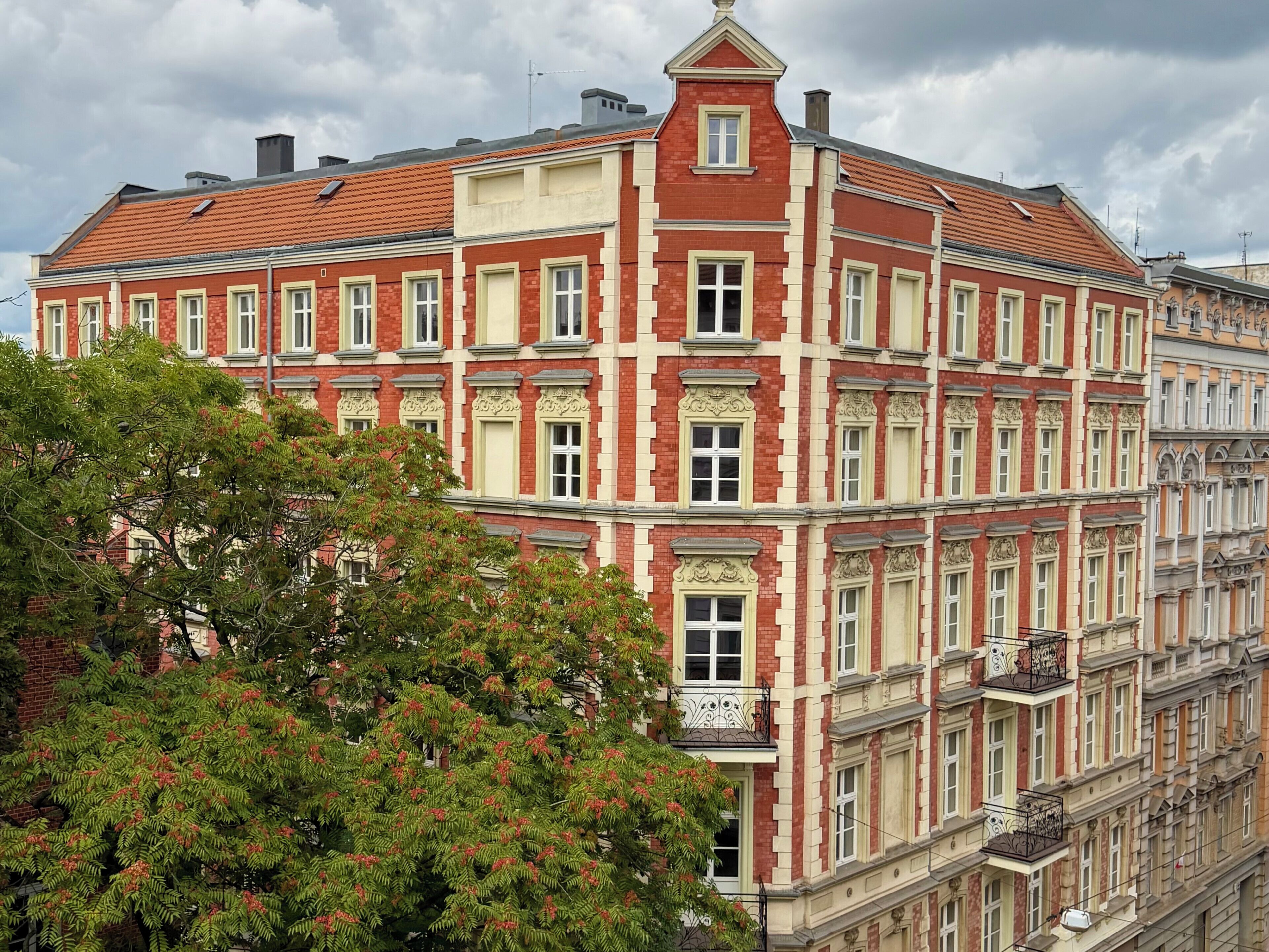 A multi-story building with a red and cream facade, large windows, and ornate architectural details.