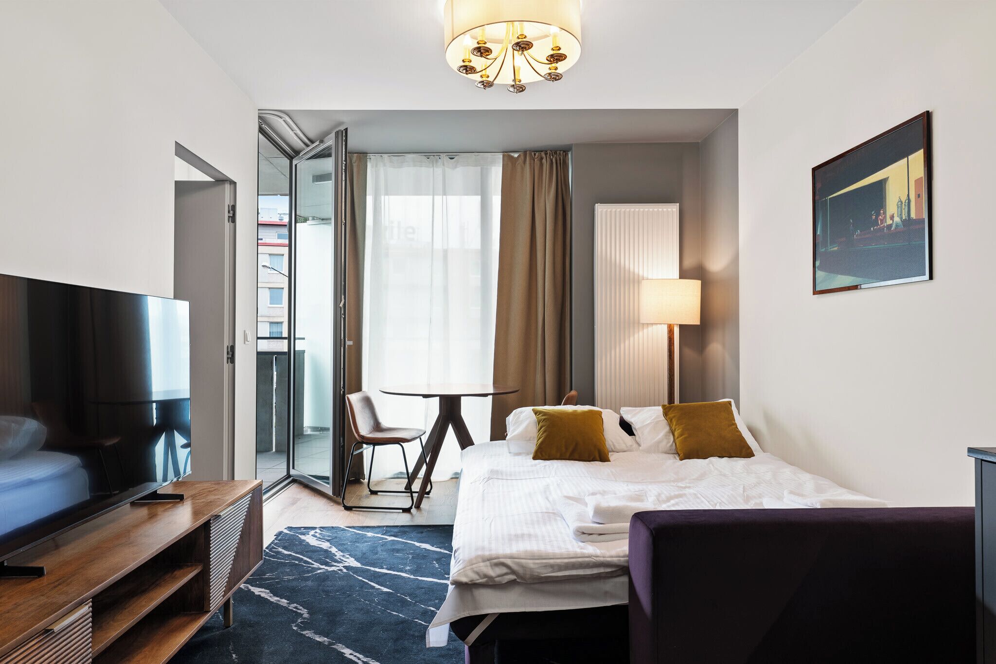 Une chambre d’hôtel avec un lit, un bureau, une chaise, une télévision et un tableau au mur.