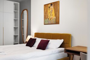A bedroom with a bed, a wooden headboard, a nightstand, a lamp, a wardrobe, and a painting on the wall. - Lubomelska City Prestige 54 Apartment (Lublin)
