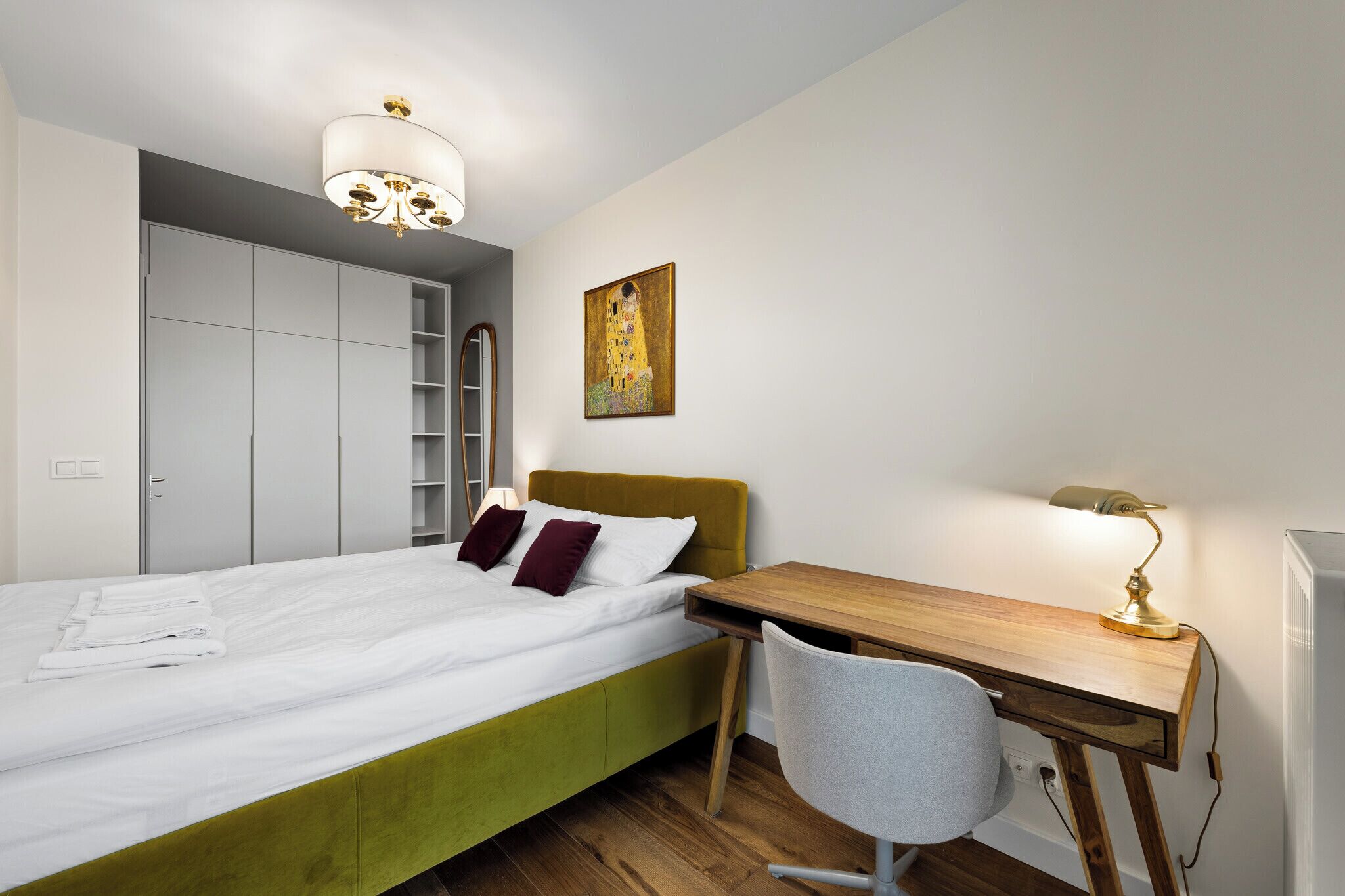 Une chambre à coucher avec un lit, un bureau, une chaise, une armoire et un tableau.