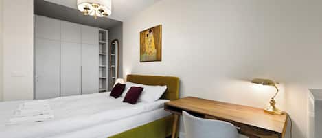 Une chambre à coucher avec un lit, un bureau, une chaise, une armoire et un tableau.