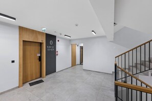Ein moderner Flur mit einer Holztür, auf der die Zahl '0' steht, und einer Treppe mit einem hölzernen Geländer.