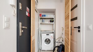 A laundry room with a washing machine, a dryer, and a vacuum cleaner. - Puławska Urban Nest Apartment (Warszawa)