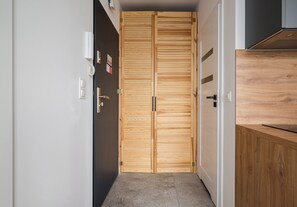 Un couloir avec une porte en bois, un interrupteur et un téléphone fixé au mur.