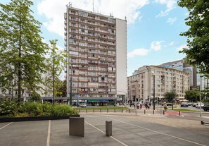 A multi-story residential building with balconies, a pedestrian crossing, and a traffic light. - Puławska Urban Nest Apartment (Warszawa)