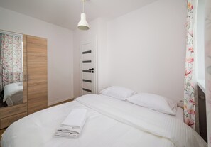 Ein Schlafzimmer mit Bett, Kleiderschrank, Spiegel und einer Deckenleuchte.