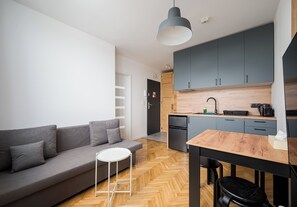 Une cuisine moderne avec des meubles gris, un plan de travail en bois et un réfrigérateur noir.