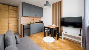 A modern kitchen with grey cabinets, a wooden countertop, and a built-in microwave. - Puławska Urban Nest Apartment (Warszawa)