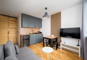 A modern kitchen with grey cabinets, a wooden countertop, and a built-in microwave. - Puławska Urban Nest Apartment (Warszawa)