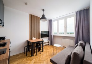 Ein modernes Wohnzimmer mit einer Couch, einem Esstisch und einem an der Wand befestigten Fernseher.