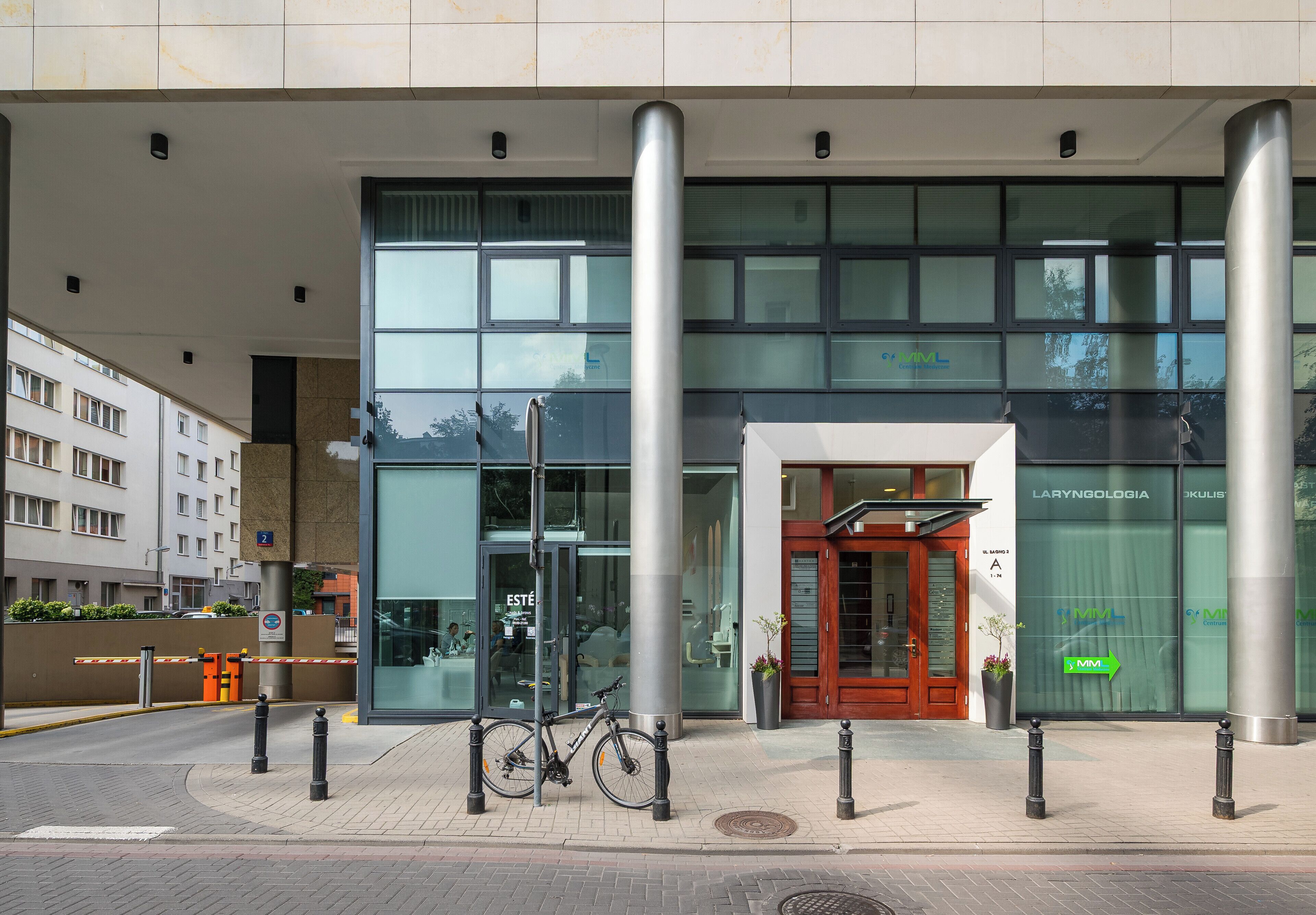 Un edificio moderno con fachada de vidrio, una bicicleta estacionada al frente y un letrero que indica un centro médico.