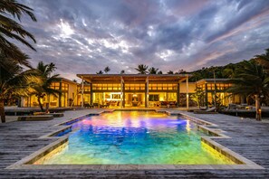 A resort with a swimming pool, palm trees, and a building with large windows.