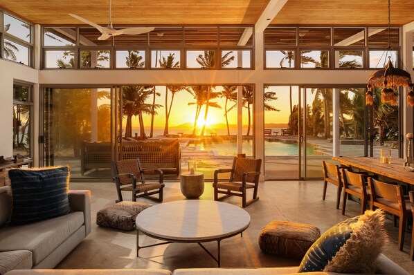 A modern interior with a pool, outdoor seating, and a view of the sunset.