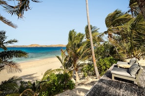 A beach with a wooden deck and lounge chairs overlooking the ocean.