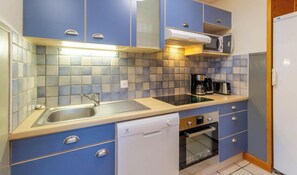A compact kitchen with a sink, dishwasher, oven, and a coffee maker.