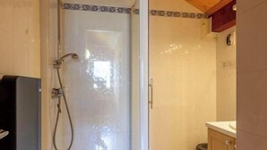 Une cabine de douche dotée d’une porte en verre, d’un plafond en bois et d’un revêtement de sol carrelé.