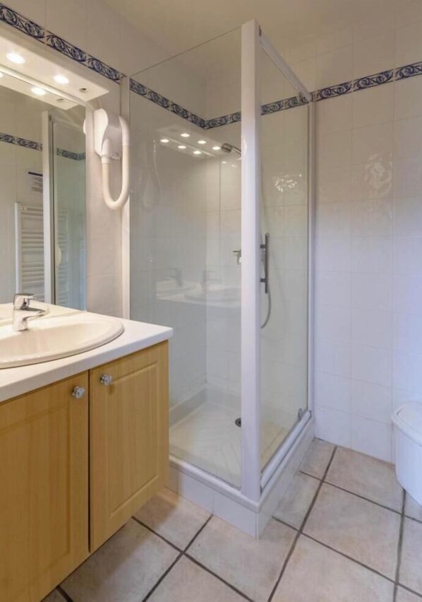 Un baño con ducha vidriada, lavamanos con espejo y muebles de madera.