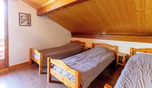 Una habitación con dos camas de madera, techo de madera y una pequeña mesa.