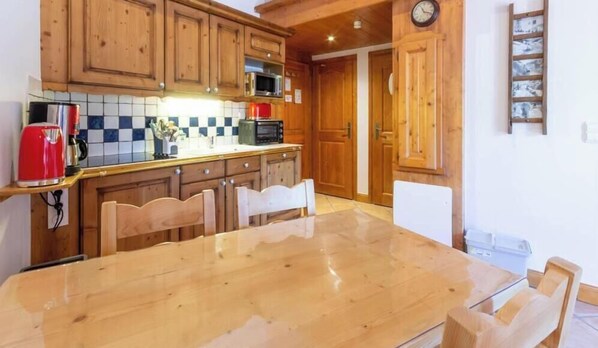 A wooden kitchen with a large table and chairs, a coffee maker, and a microwave.