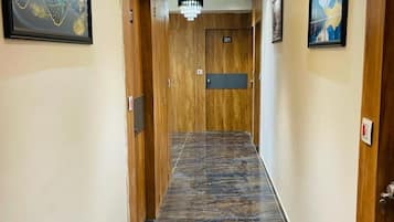 A hotel hallway with wooden doors, marble flooring, and artwork on the walls.
