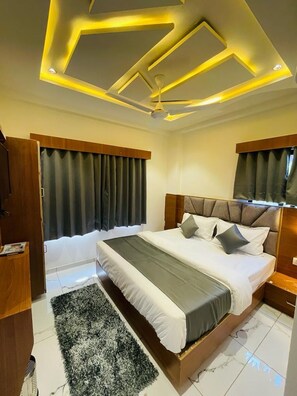 Un dormitorio con cama, cortinas, una lámpara en el techo y un cabecero de madera.