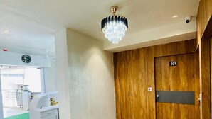Un vestíbulo de hotel con una puerta de madera marcada '201', un candelabro y un mostrador de recepción.