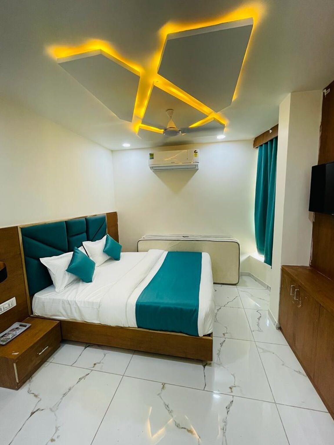 Un dormitorio moderno con cama, televisor y lámpara en el techo.