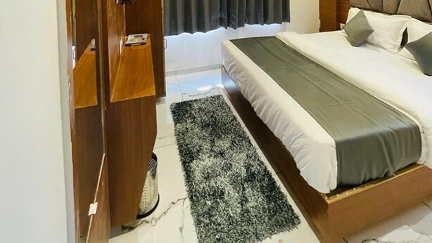 Un dormitorio moderno con cama, armario de madera, espejo e iluminación geométrica en el techo.