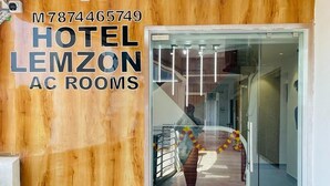 Entrada de hotel con fachada de madera y puerta de cristal que da a un pasillo.