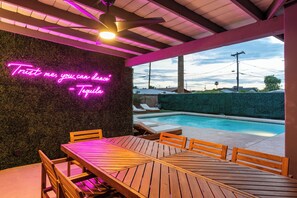 Eine Terrasse im Freien mit einem Neonlicht, einem Pool und Blick zum Himmel.