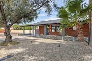 A building with a brick facade, a covered patio area, and a palm tree. - Scottsdale Old Town Palm Oasis 🌵⛳ Heated Pool, Ping Pong Near Old Town (Scottsdale)