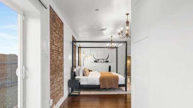 A bedroom with a brick wall, a bed with a canopy, and a chandelier. - 4BR Old Town Scottsdale Retreat | Heated Pool, Ping Pong & Cornhole (Scottsdale)