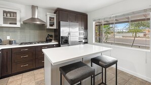 A modern kitchen with a central island, stainless steel appliances, and a view of the street through large windows. - 4BR Old Town Scottsdale Retreat | Heated Pool, Ping Pong & Cornhole (Scottsdale)