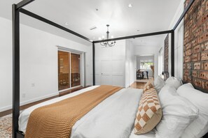 Ein Schlafzimmer mit Himmelbett, einer Ziegelwand und Blick in den Essbereich.