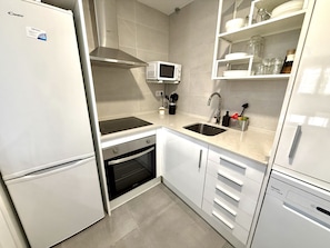 A modern kitchen with white cabinetry, a built-in microwave, a stainless steel sink, and a dishwasher. - SR Playa de los Boliches 2-Bedroom Apartment, Downtown Fuengirola (Fuengirola)