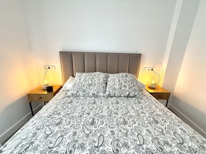 A bed with a patterned bedspread, two bedside lamps, and a headboard. - SR Playa de los Boliches 2-Bedroom Apartment, Downtown Fuengirola (Fuengirola)