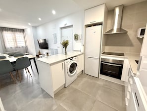 A compact kitchen with a built-in washing machine, a microwave, and a stove. - SR Playa de los Boliches 2-Bedroom Apartment, Downtown Fuengirola (Fuengirola)